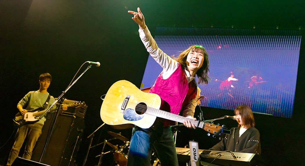 ギターを手にステージに立つ女性